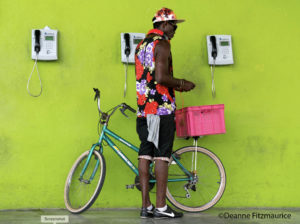 Deanne Fitzmaurice photo bicycle rider in colorful clothes in front of lime green wall, cuba